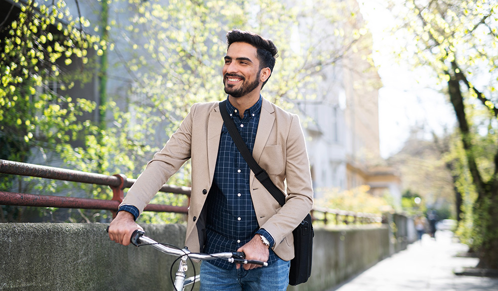 A middle-aged man walks outside steering his bicycle. Regular exercise reduces colorectal cancer risk as part of a healthy lifestyle.
